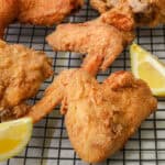 Crispy Fried Louisiana Fried Chicken on cooling rack with lemon wedges