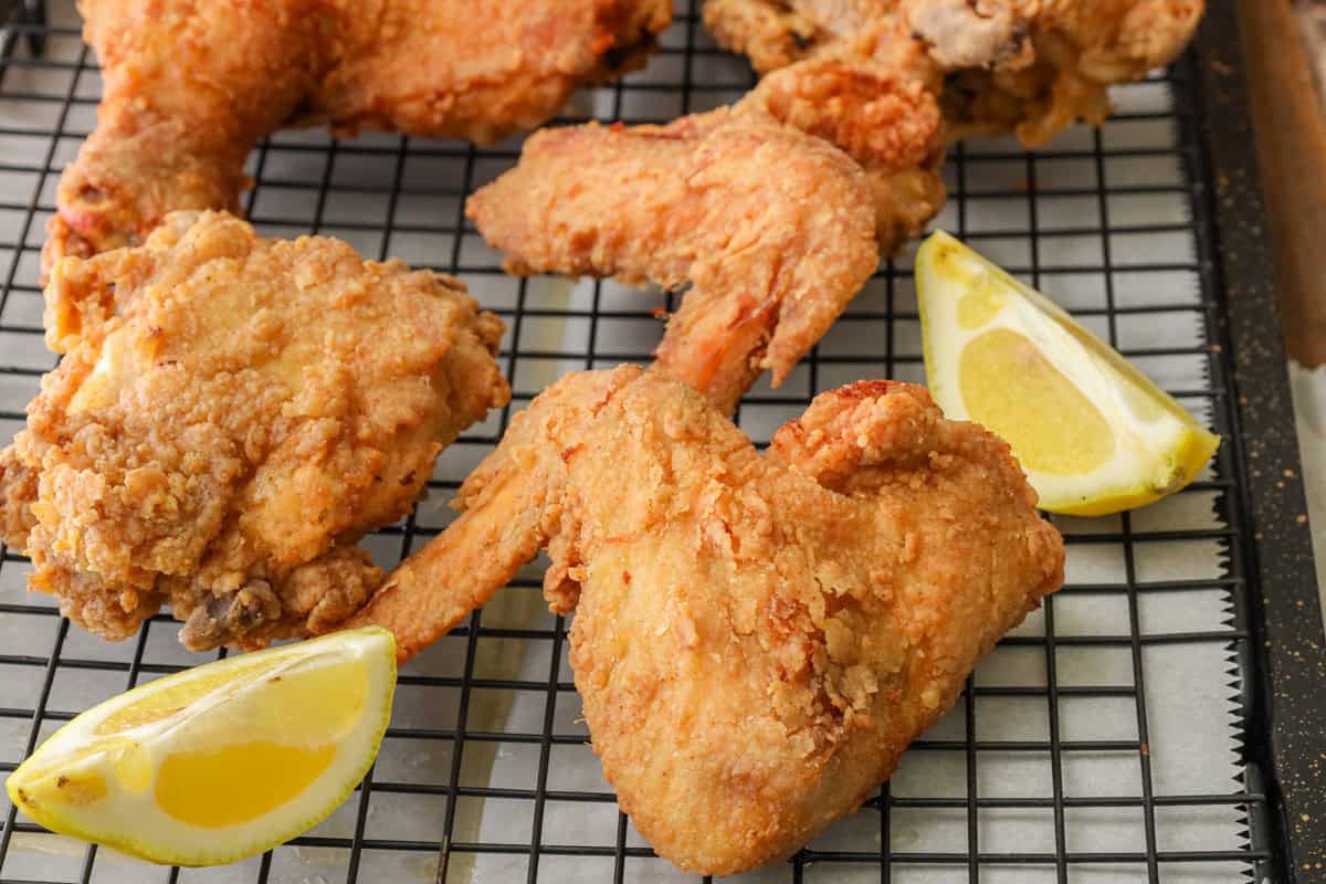 Crispy Fried Louisiana Fried Chicken on cooling rack with lemon wedges