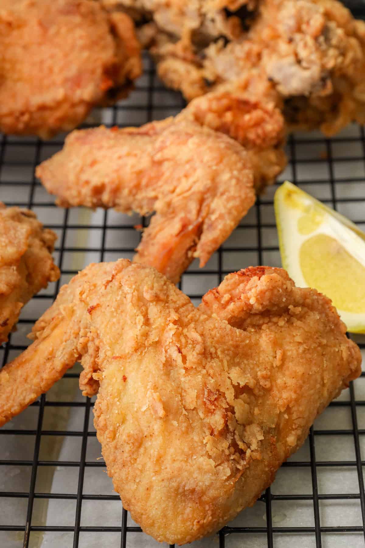 Crispy Fried Louisiana Fried Chicken on cooling rack with lemon wedges