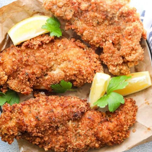 crispy fried catfish on brown paper with lemon wedges