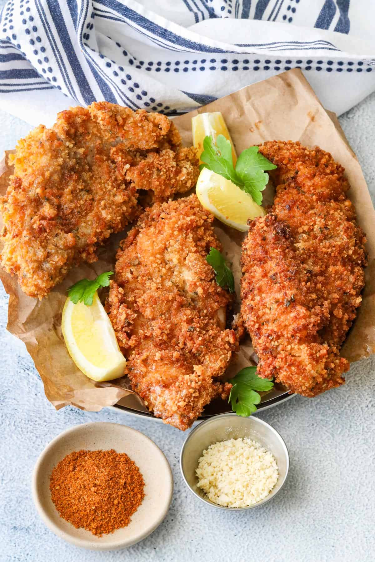 fried catfish with lemon wedges on white board and old bay seasoning with breadcrumbs