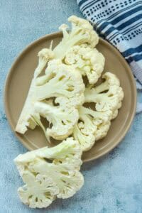 raw cauliflower steaks on brown plate