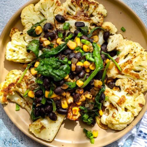 cauliflower steaks toped with black beans, corn, and spinach