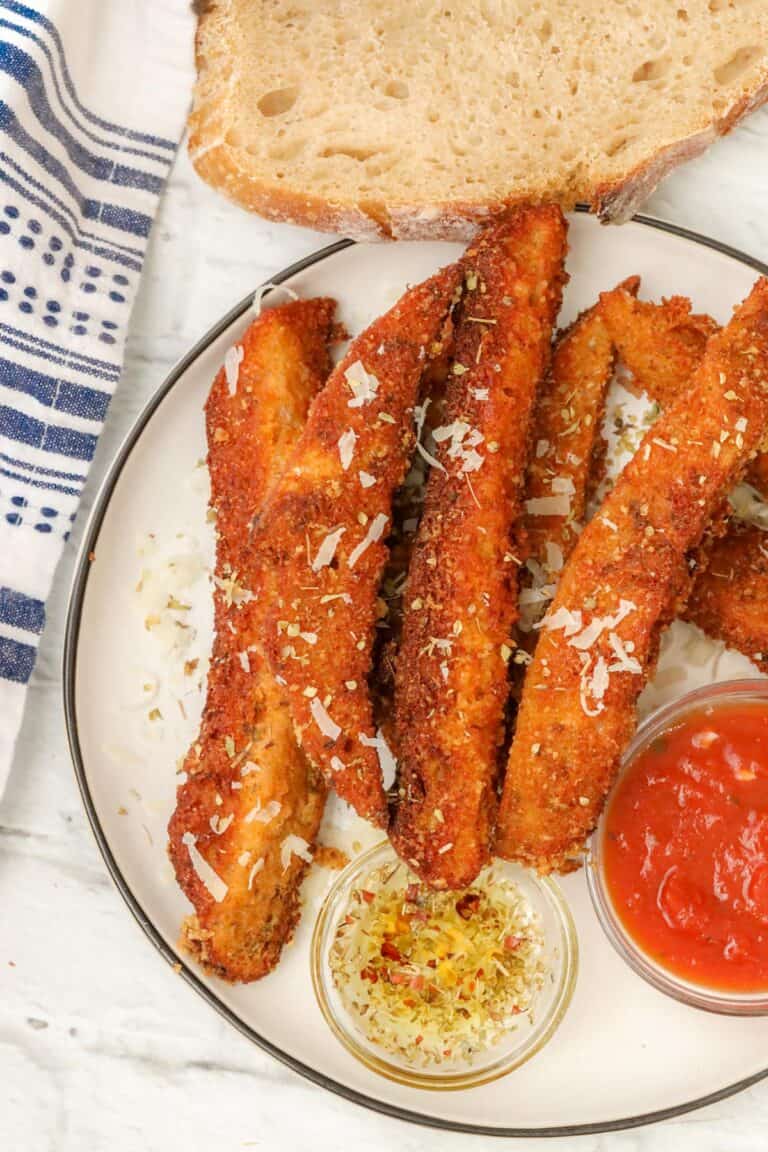 Sourdough Breadsticks topped with shaved parmesan cheese with marinara sauce and olive oil on the side