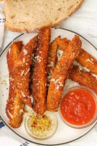 sourdough breadsticks on plate with marinara sauce and olive oil