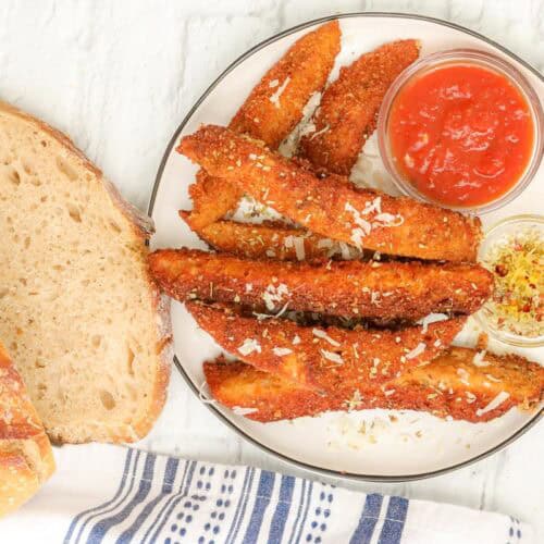 sourdough breadsticks on plate with marinara sauce and olive oil