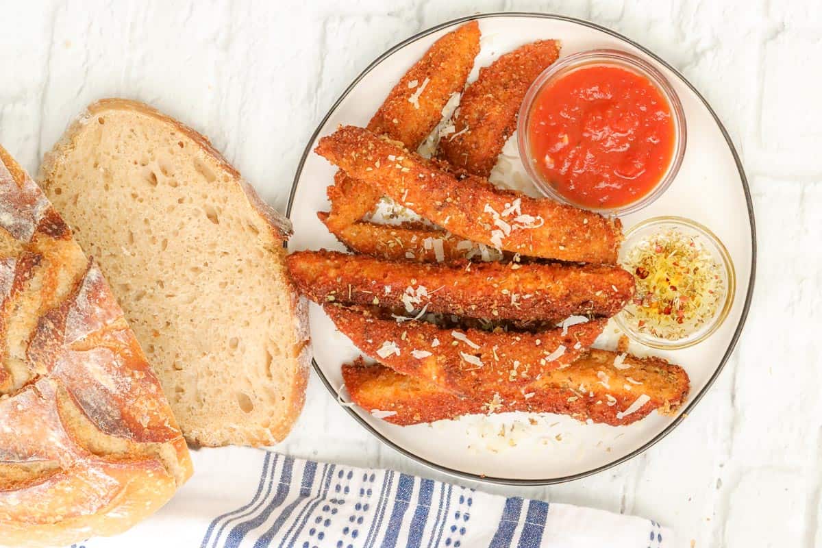 sourdough breadsticks on plate with marinara sauce and olive oil
