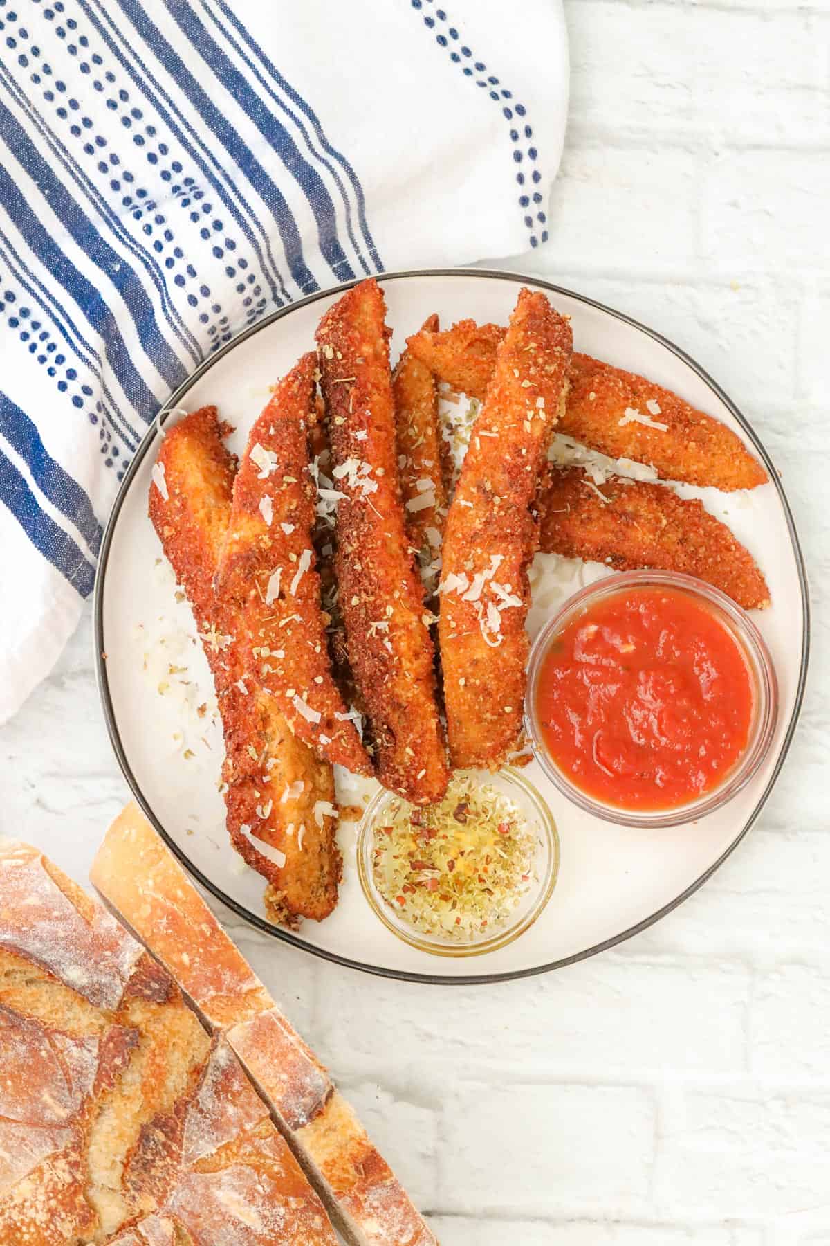 sourdough breadsticks on plate with marinara sauce and olive oil