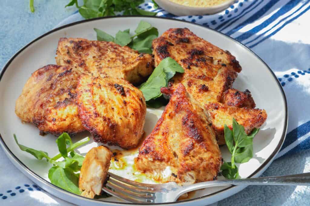 Fried chicken breast on white plate topped with herbs