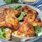 Fried chicken breast on white plate topped with herbs