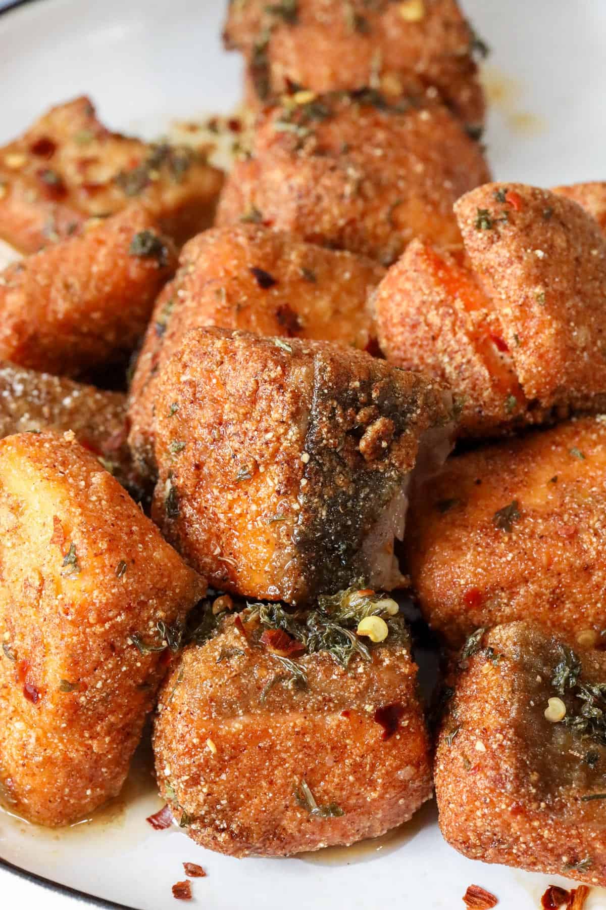 fried salmon bites with lemon-oil sauce on white plate