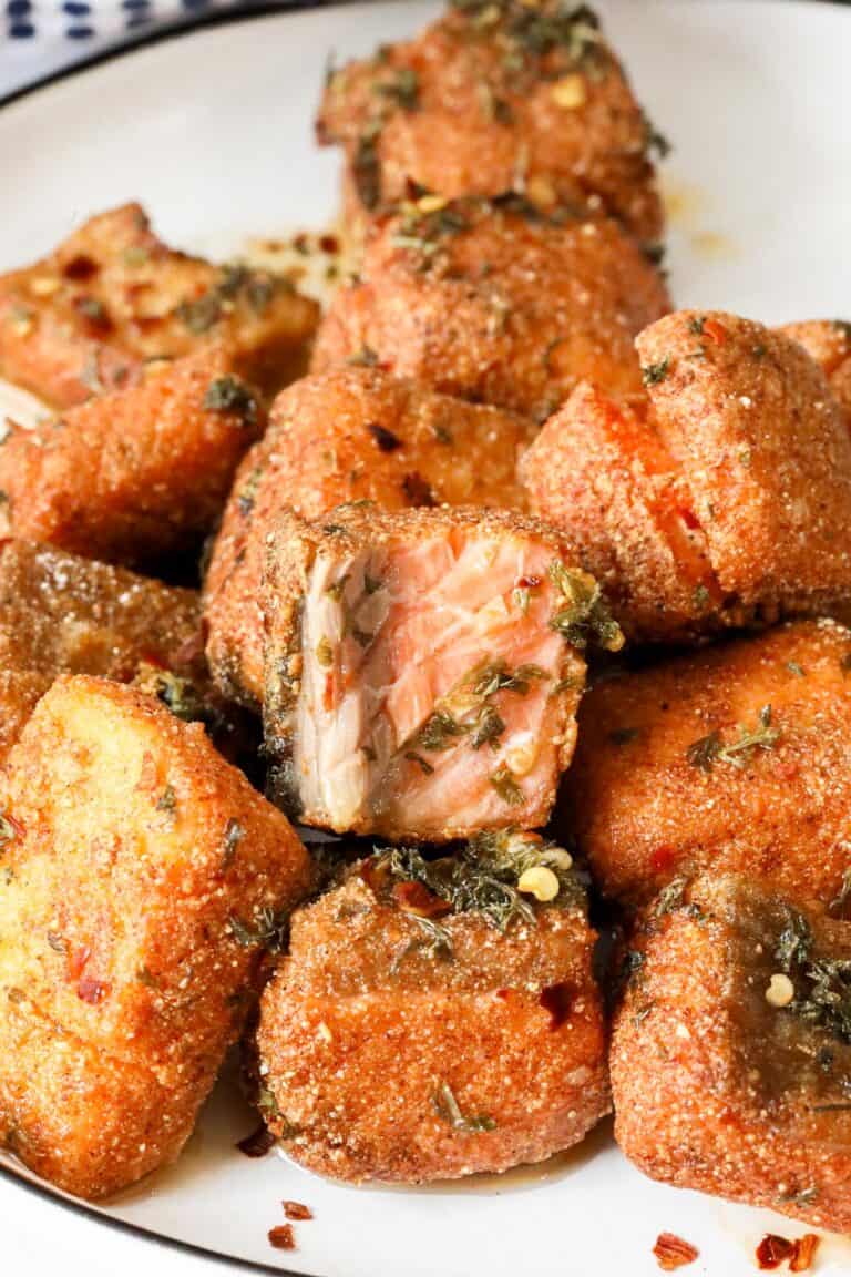 fried salmon bites with lemon-oil sauce on white plate