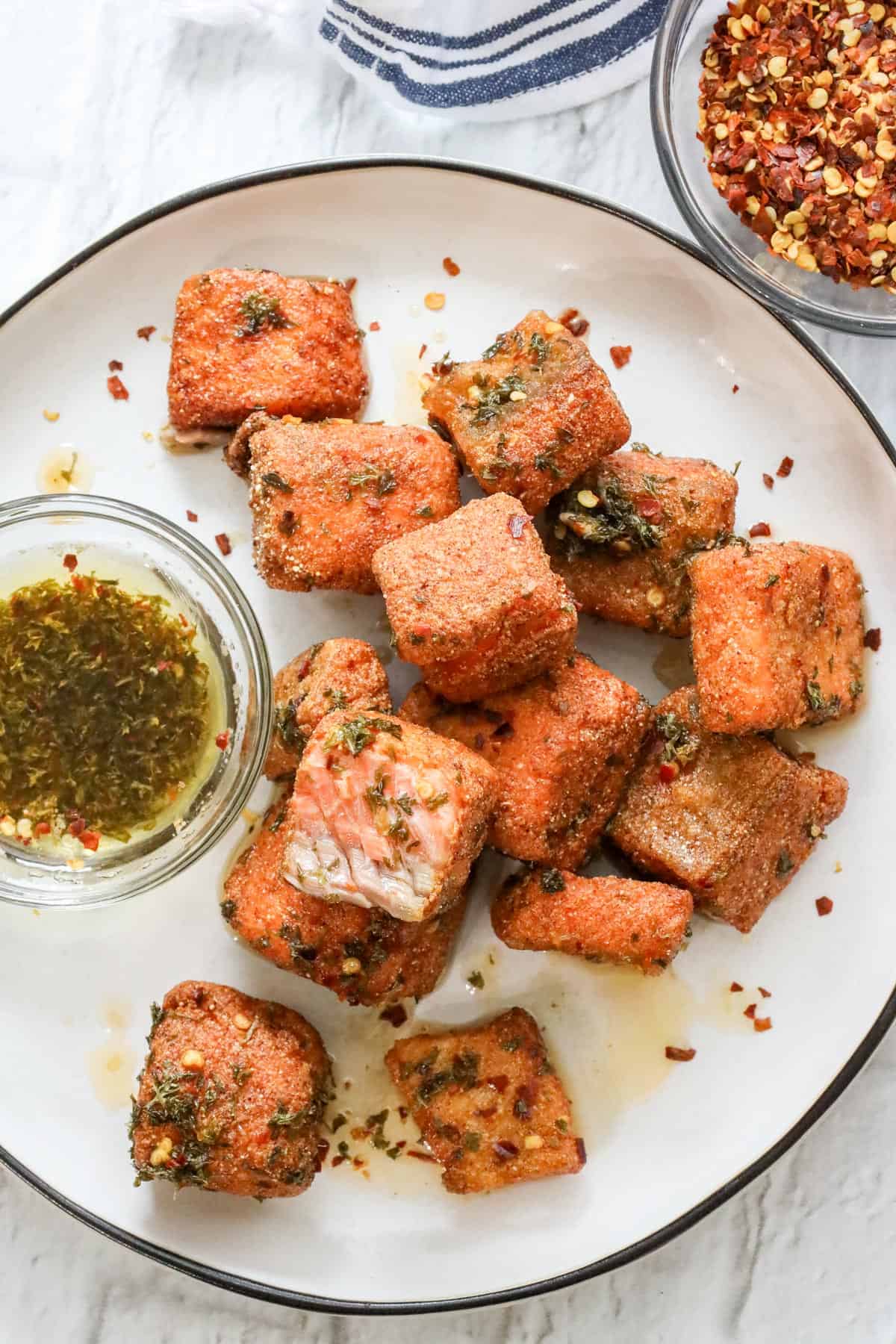 fried salmon bites with lemon-oil sauce on white plate