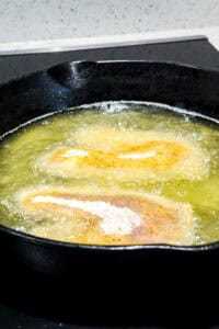 fried breaded tilapia in cast iron skillet
