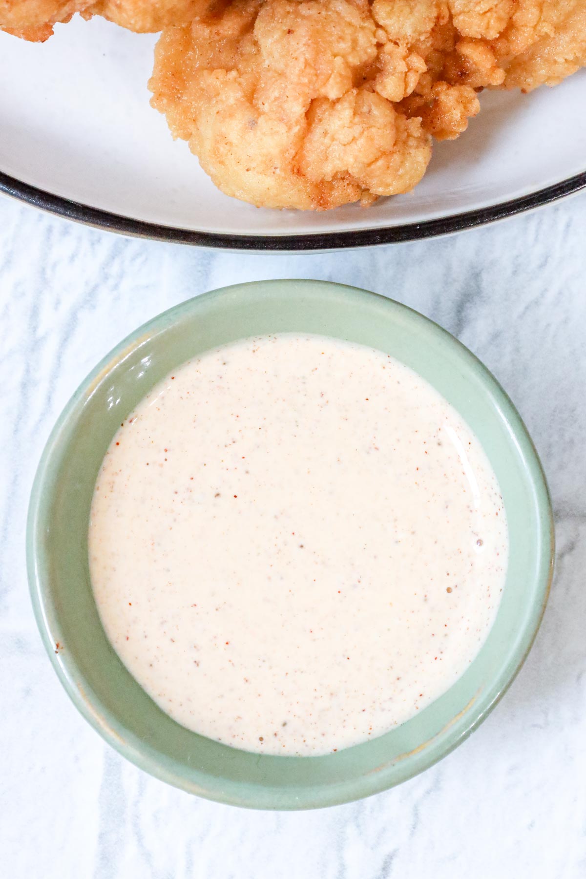 creamy sauce for chicken with fried chicken tenders on white plate