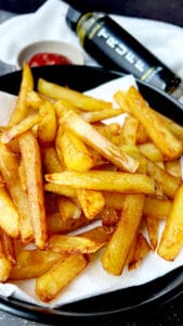 deep fried truffle fries on black plate with Truff and ketchup on the side