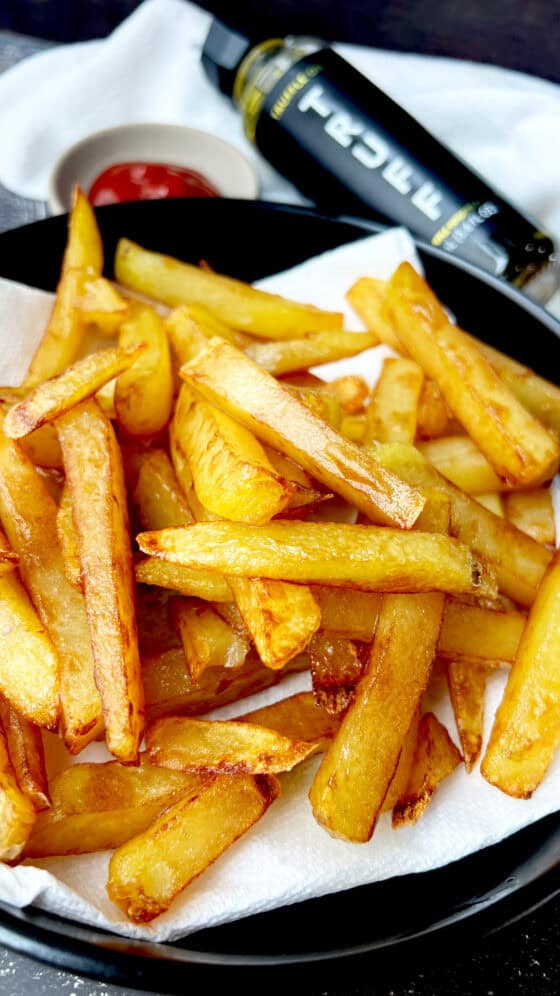 deep fried truffle fries on black plate with Truff and ketchup on the side