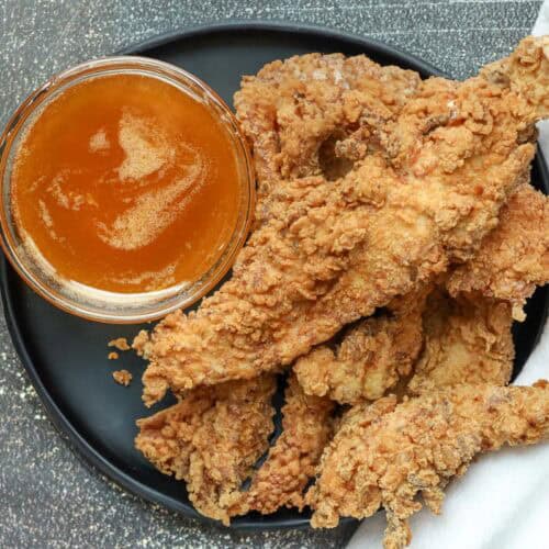 Southern Fried Chicken strips with sauce on black plate