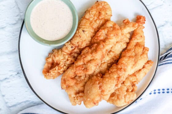 creamy sauce for chicken with fried chicken tenders on white plate