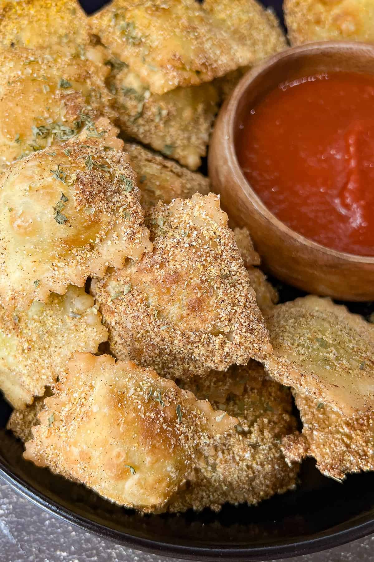 Fried Raviolini on black plate with marinara sauce