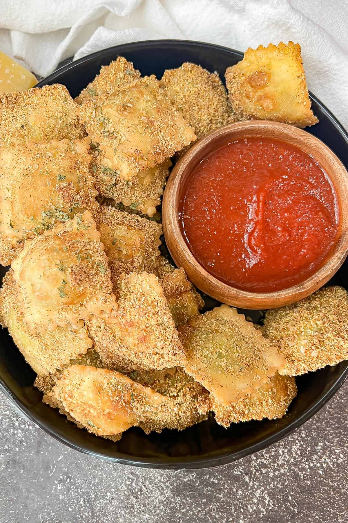 Fried Raviolini on black plate with marinara sauce