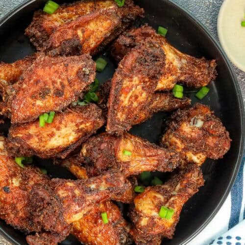 Fried Soy Sauce Garlic Chicken Wings in black bowl topped with green onions