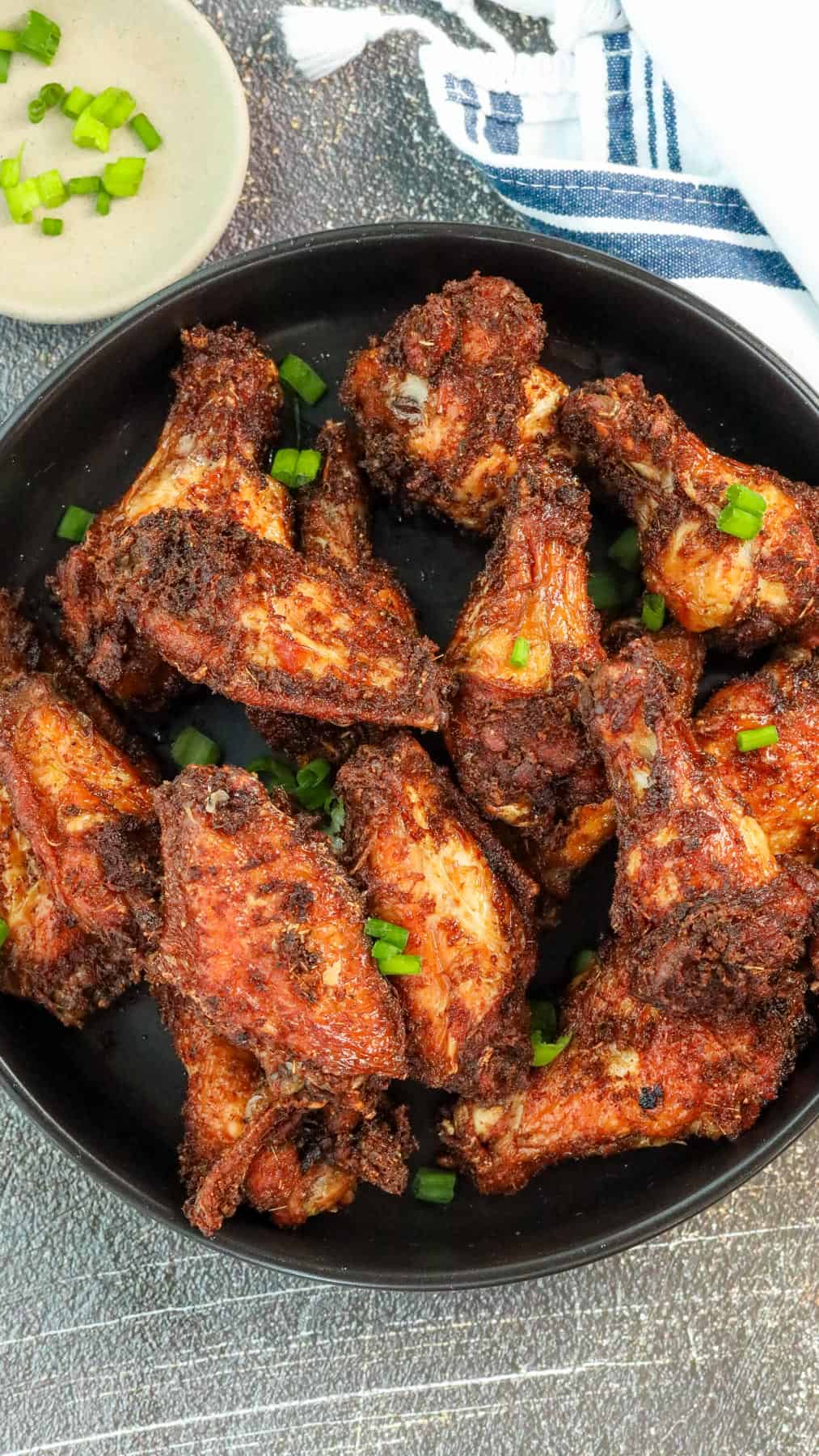 Fried Soy Sauce Garlic Chicken Wings in black bowl topped with green onions