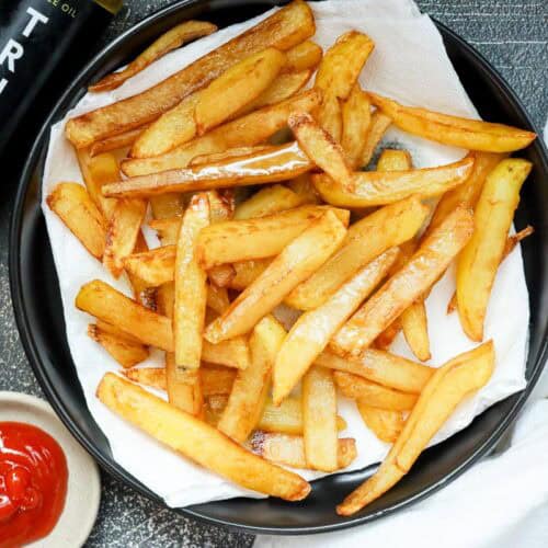 deep fried truffle fries on black plate with Truff and ketchup on the side