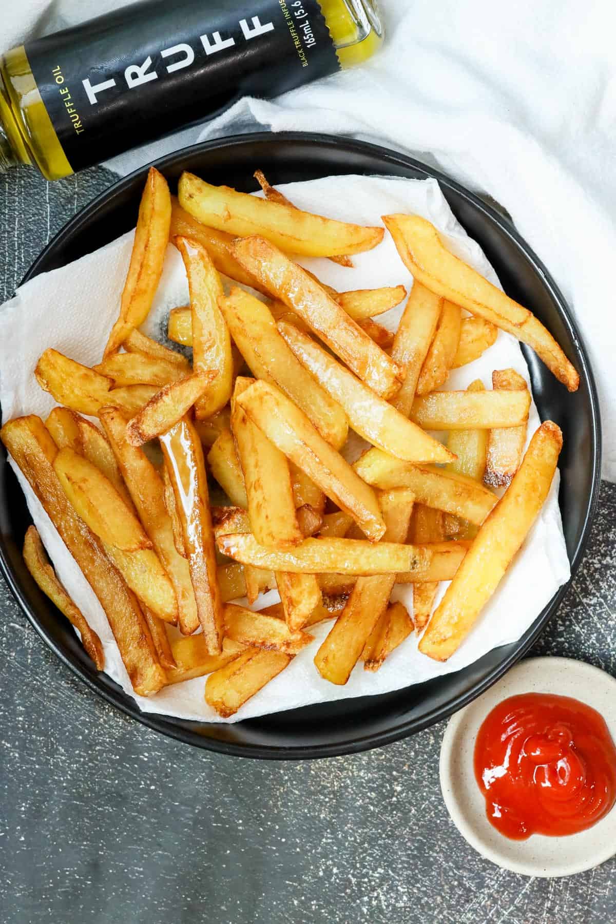 deep fried truffle fries on black plate with Truff and ketchup on the side
