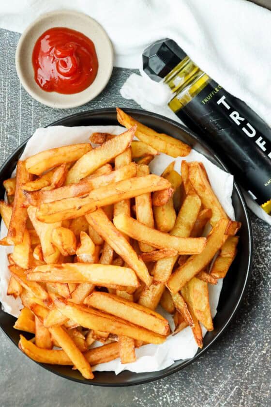 deep fried truffle fries on black plate with Truff and ketchup on the side