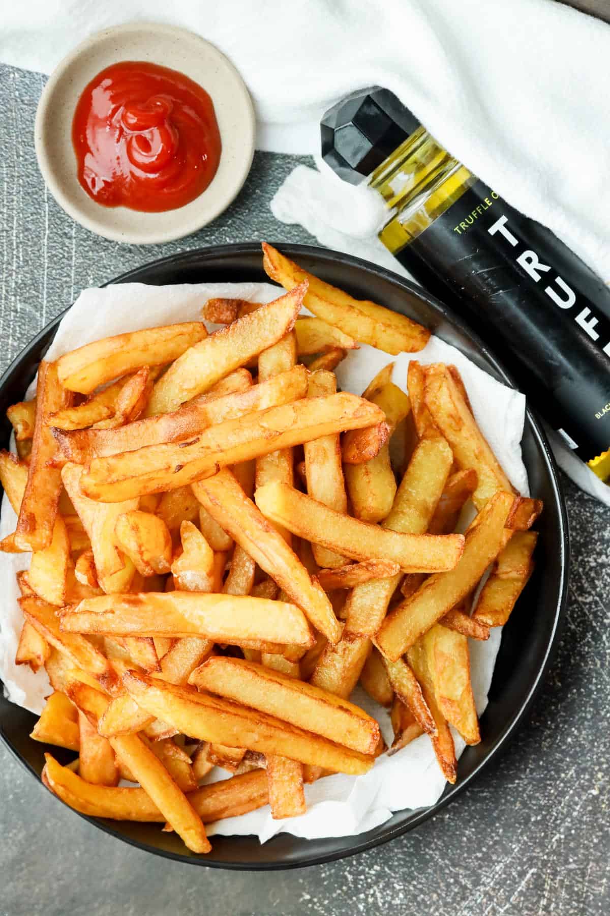deep fried truffle fries on black plate with Truff and ketchup on the side