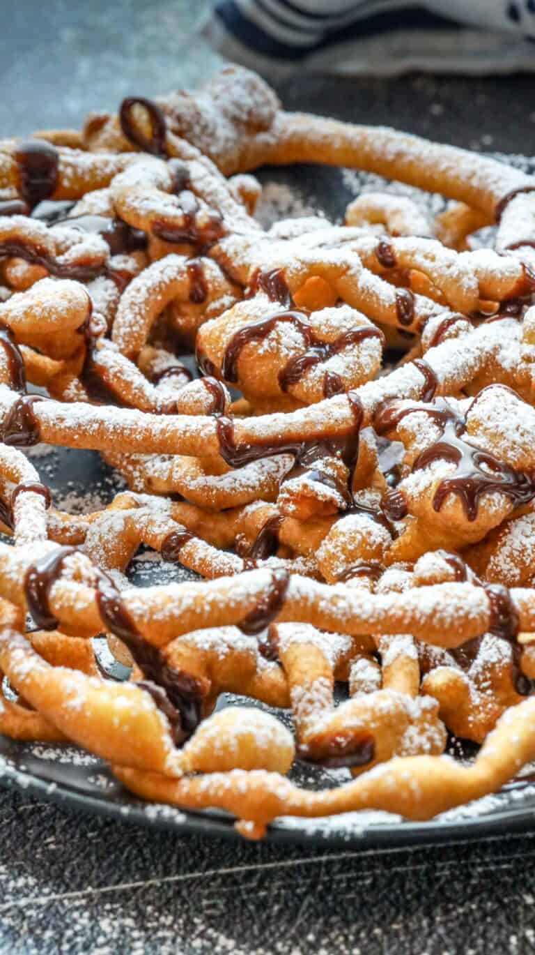 funnel cake made at home dusted with powdered sugar and drizzled with chocolate