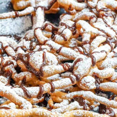 funnel cake made at home dusted with powdered sugar and drizzled with chocolate