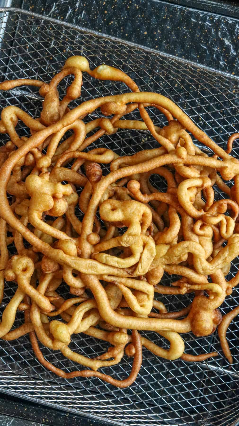 fried homemade funnel cake in cooling rack