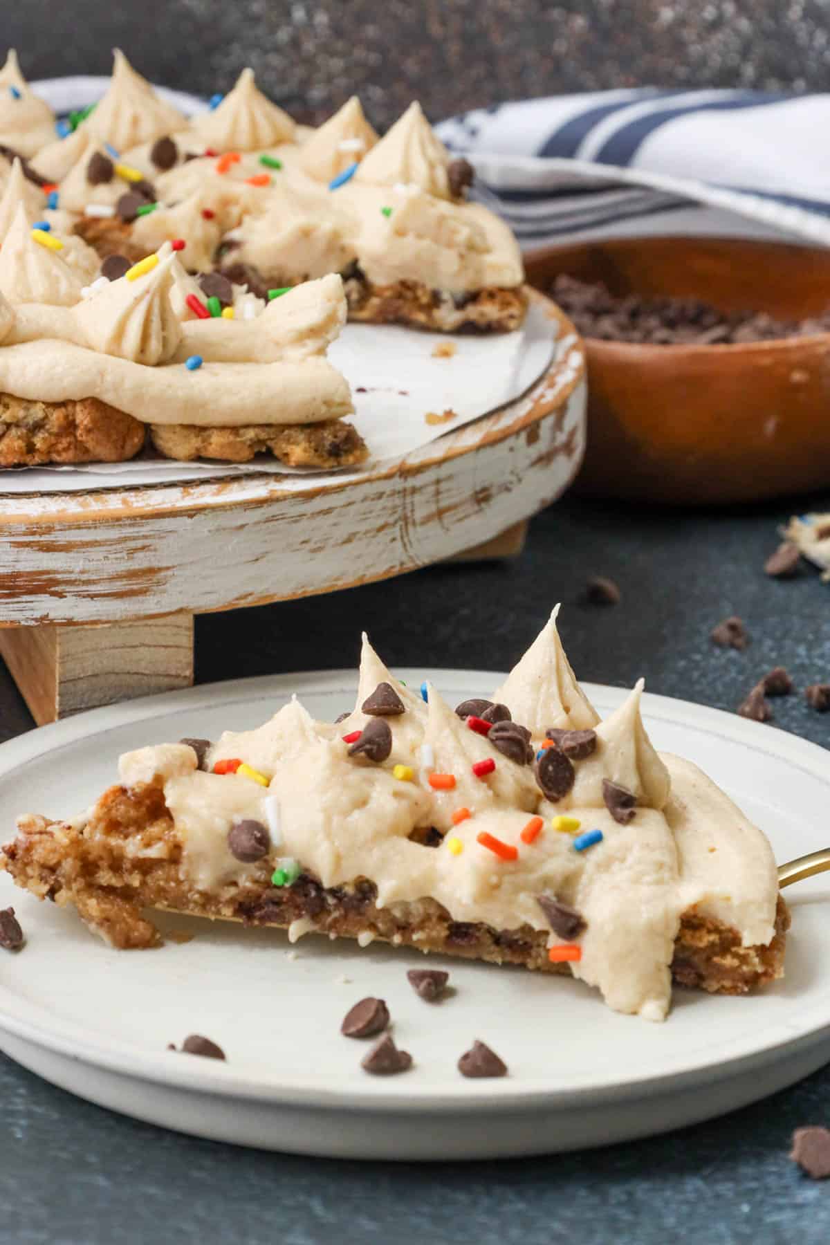 sliced air fryer cookie cake topped with sprinkles and chocolate chips and vanilla frosting 
