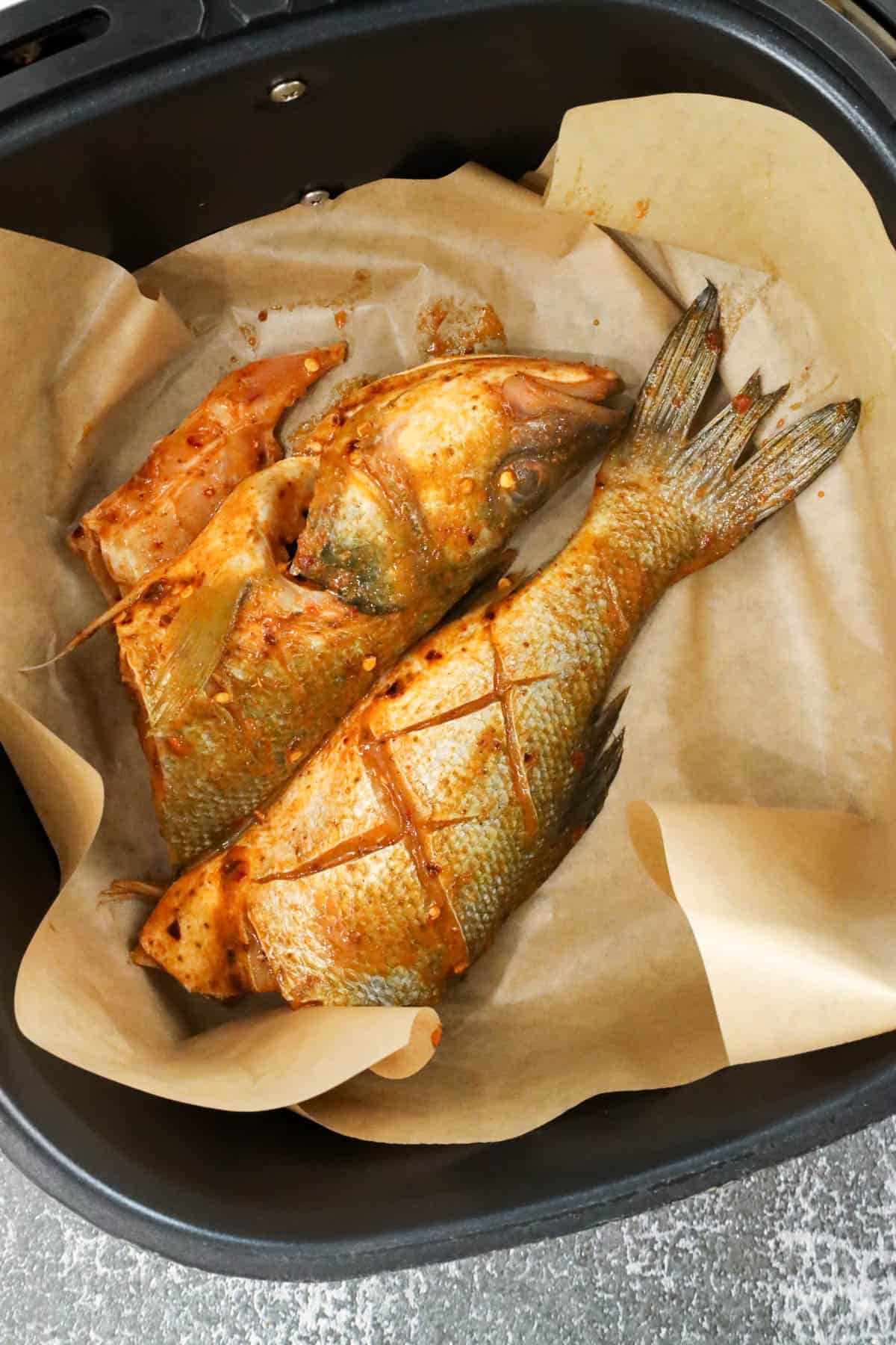 branzino fish cut in half with slits on parchment paper to air fry