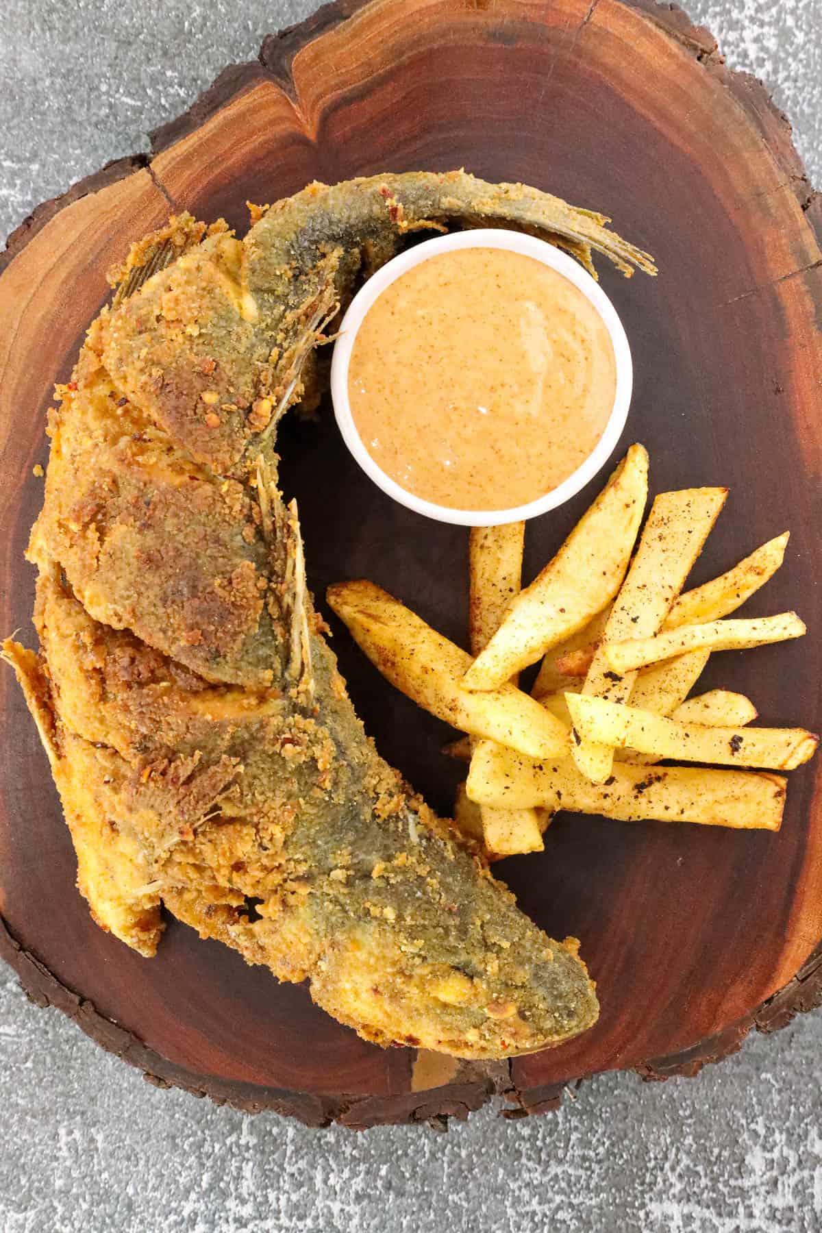 fried branzino on wooden board with French fries