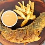 fried branzino on wooden board with French fries