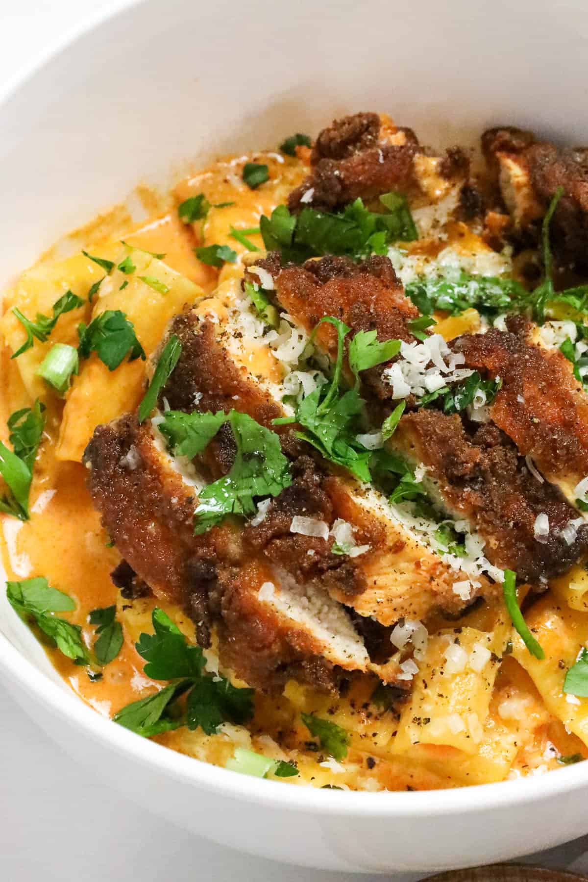 Delicious Gochujang Chicken Breast Recipe over a bed of gochujang pasta and topped with fresh herbs and cheese