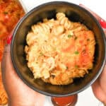 Hand holding a a bowl of buffalo Mac and cheese