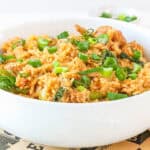 Bowl of homemade gochujang fried rice with chicken, broccoli, and green onions garnished with fresh scallions.