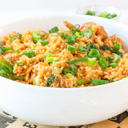 Bowl of homemade gochujang fried rice with chicken, broccoli, and green onions garnished with fresh scallions.
