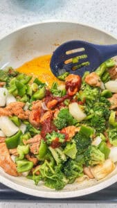 Chicken, broccoli, bell peppers, onion, garlic, and green onions sautéing in a skillet for gochujang fried rice.