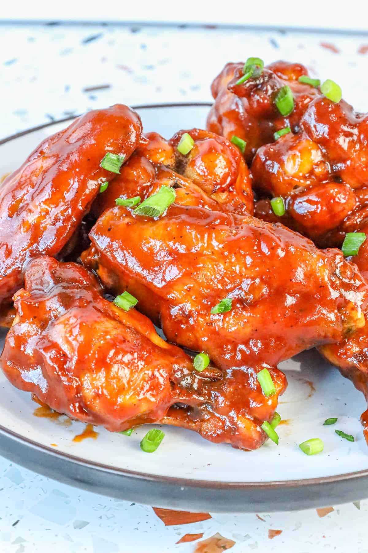 honey bbq chicken wings topped with chives on plate