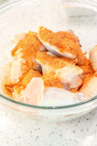 season on top of wings in a glass bowl